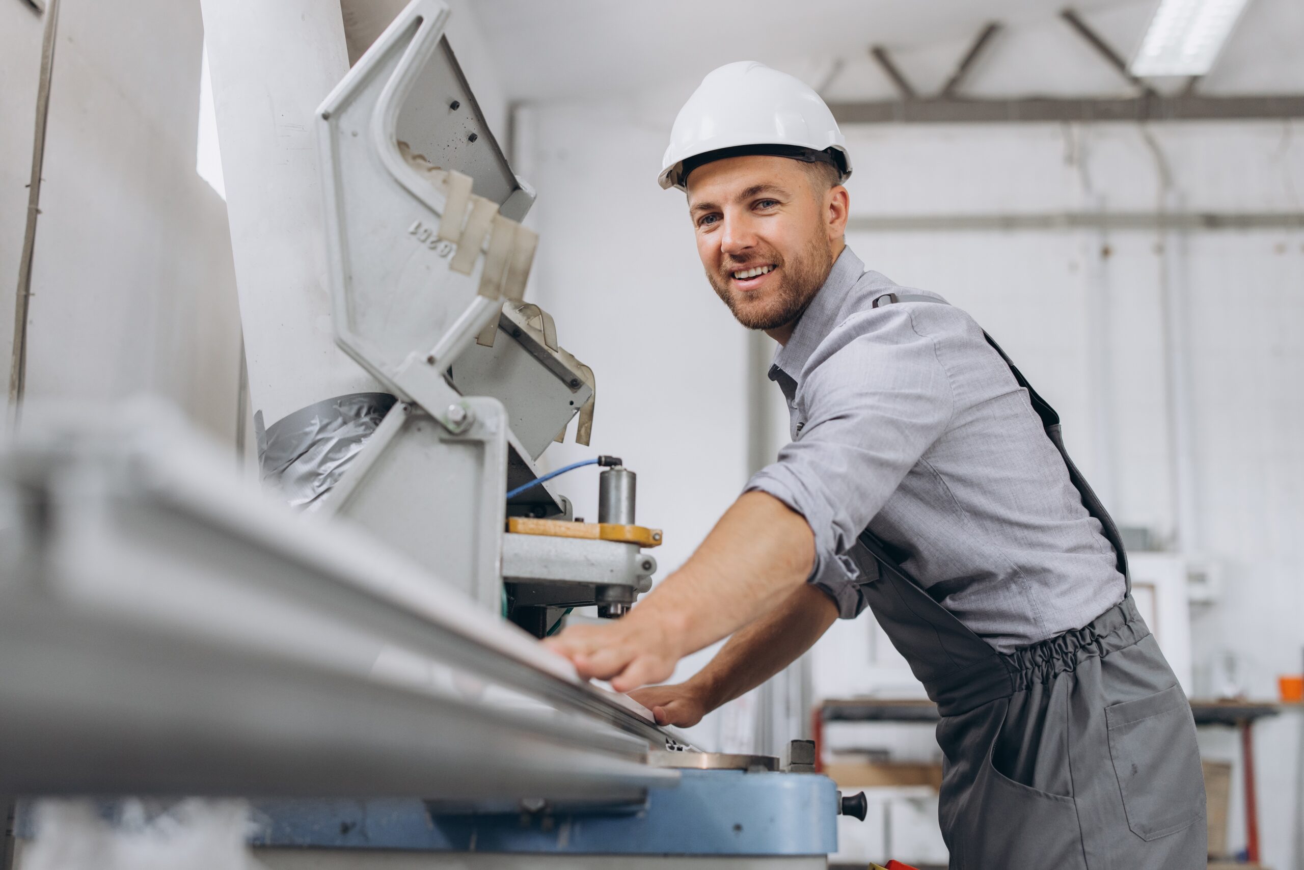 Fabrication technician operating hydraulic tools on conveyor belt in industrial warehouse